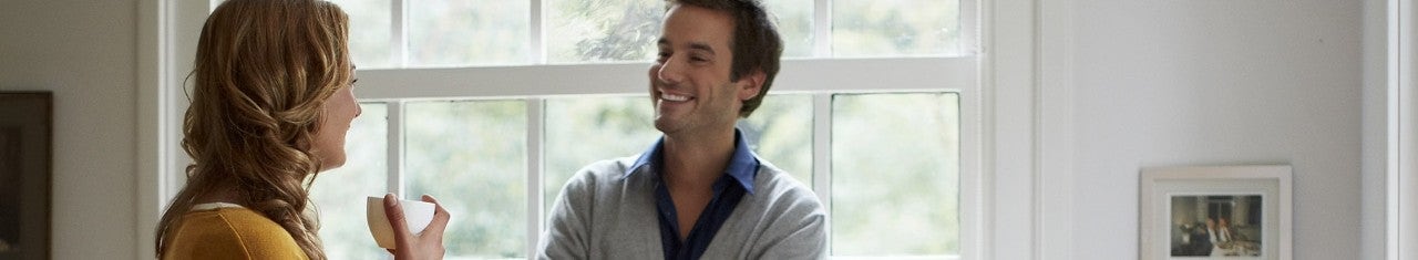 Woman holding a cup while speaking to a man